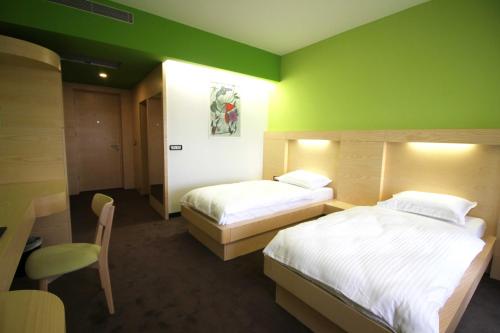 a bedroom with two beds and a green wall at Hotel International Prishtina & Spa in Pristina
