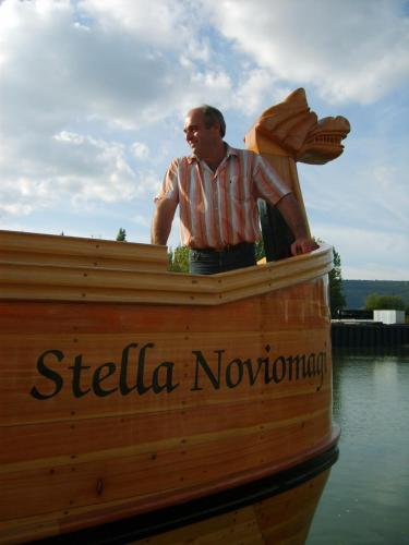 a man standing on the front of a wooden boat at Ferienwohnungen Schneider-Kettern in Neumagen-Dhron