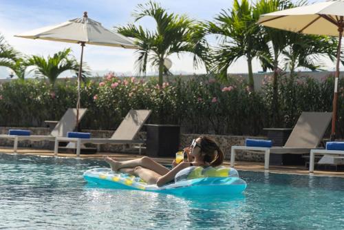 a woman laying on a raft in the water in a swimming pool at Royal Phuket City Hotel in Phuket