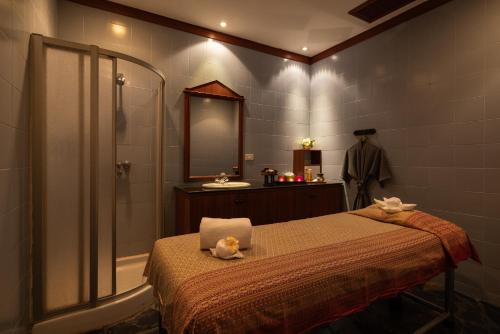 een badkamer met een bed, een douche en een wastafel bij Royal Phuket City Hotel in Phuket