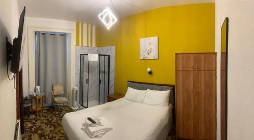 ein Schlafzimmer mit einem weißen Bett und einer gelben Wand in der Unterkunft Savoy Hotel in Weston-super-Mare