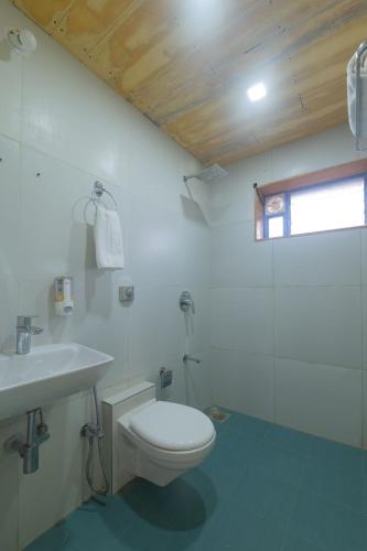 a white bathroom with a toilet and a sink at Saachi Villa in Panchgani
