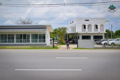 une personne debout devant un bâtiment blanc dans l'établissement บ้านพักคุณอร, à Ban Ku Sua