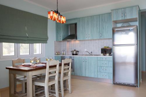 a kitchen with blue cabinets and a table and a refrigerator at Amalia Apartments in Exanthia