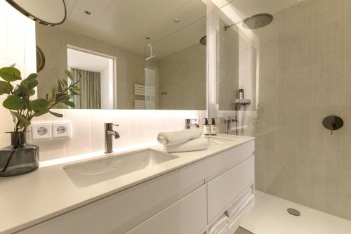 a white bathroom with a sink and a mirror at BLOOM-Living in Linz