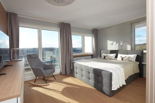 a bedroom with a bed and a chair and windows at Villa Orange Tree in Bernkastel-Kues