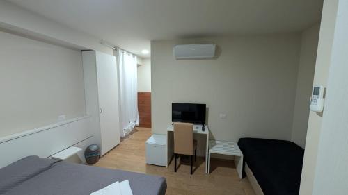 een slaapkamer met een bed, een bureau en een televisie bij L'Ulivo in Almè