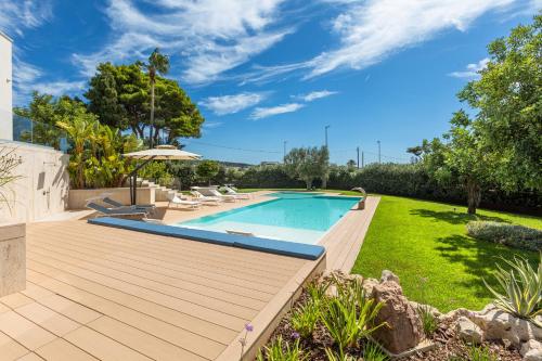 een achtertuin met een zwembad en een houten terras bij Radiluxe - Villa Marlux in Marina di Pescoluse