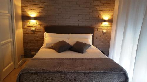 a bed with two pillows and a brick wall at Alma Hotel in Palermo