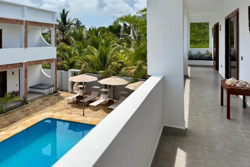 an open balcony with a pool and tables and chairs at Shirley Boutique Hotel in Kiwengwa