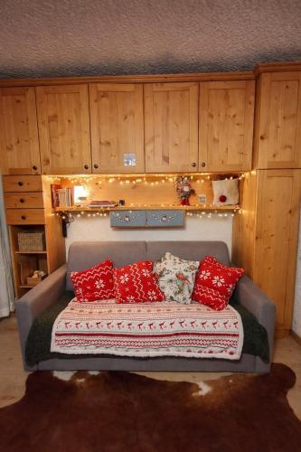 a couch with red pillows in a room with wooden cabinets at Lo Gnomo Apartment in Marilleva