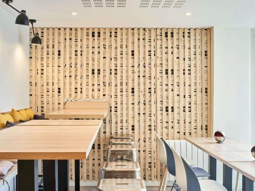 a dining room with tables and chairs and a wall with a pegboard at Aparthotel Adagio Access Paris Saint-Denis Pleyel in Saint-Denis
