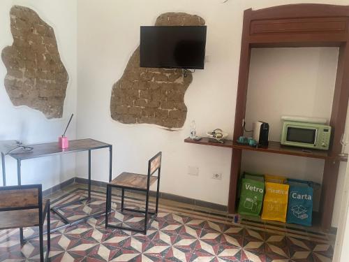 een kamer met een tafel en een tv aan de muur bij Luxar Suites & Apartments in Assemini