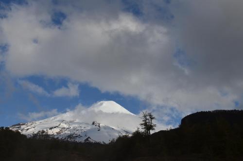 a snow covered mountain in the sky with clouds at Departamento Pucon in Pucón