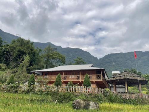 a house in a field with a flag and mountains at Lee's Charm Homestay in Sa Pa