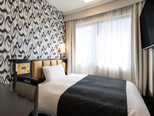 a hotel room with a bed and a window at APA Hotel STAY Toyama in Toyama