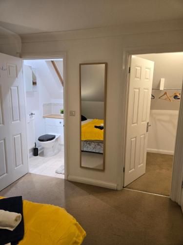 a bedroom with a yellow bed and a mirror at Duxford Haven in Duxford