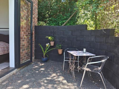 a patio with a table and chairs next to a wall at Lakritz A Place of Experience through Art in Chintsa