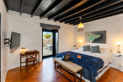a bedroom with a bed and a table and a television at La Geria Suites in Yaiza