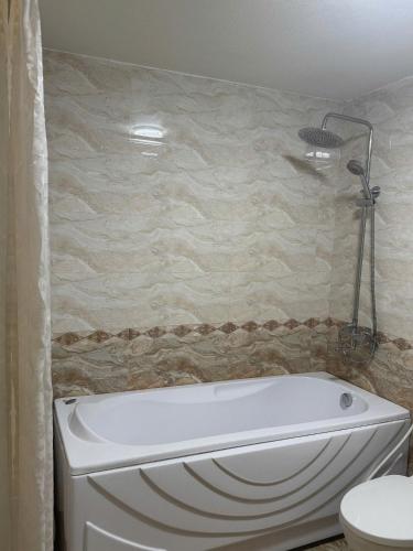 a white bath tub in a bathroom with a toilet at AVS Nội Bài Hotel in Sóc Sơn
