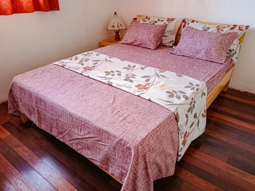 a bedroom with a bed with a purple and white blanket at Maison Hely Tiana in Antananarivo