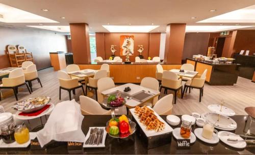 a restaurant with tables and chairs with food on them at Palette Hi Hotel Bangkok in Makkasan