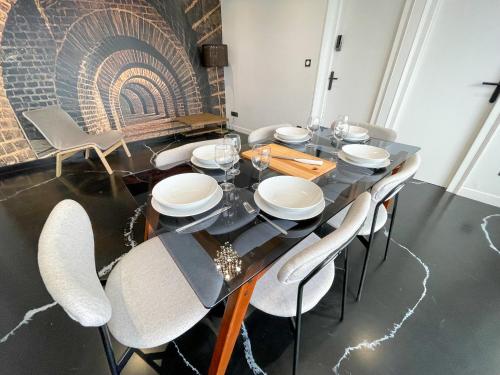 a dining room with a black table and white chairs at Atypaluxe Appartement 3 chambres in Épinal