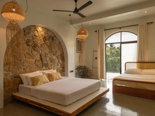 a bedroom with two beds and a stone wall at Roaming Retreat Ahangama in Ahangama