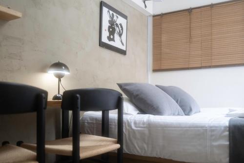 a bedroom with a bed with two chairs and a lamp at Kaku Studio Apartment Ikebukuro in Tokyo