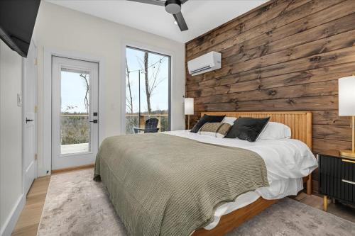 a bedroom with a bed and a wooden wall at *Rooftop Deck*Hot Tub*Sauna*Fire Pit*Sunset Views* in Campton