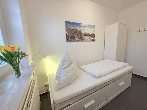 a room with a bed and a vase of flowers at Ferienwohnung KüstenSAND in Norden
