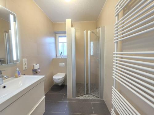 a bathroom with a shower and a toilet and a sink at Ferienwohnung KüstenSAND in Norden