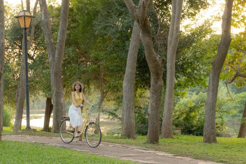 a woman riding a bike in a park at Comsaed River Kwai Resort in Kanchanaburi City