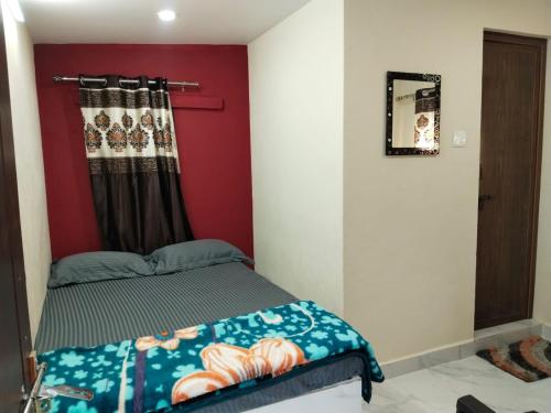 ein Schlafzimmer mit einem Bett und einer roten Wand in der Unterkunft Hegde Farmstay in Udupi