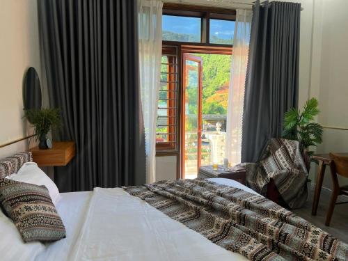 a bedroom with a bed and a large window at Đá Gió Hà Giang Homestay in Ha Giang