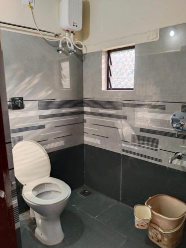 a bathroom with a toilet and a window at Hegde Farmstay in Udupi