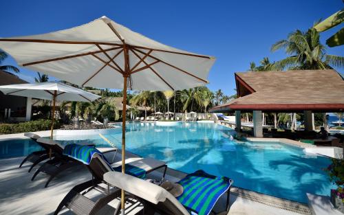 a swimming pool with chairs and an umbrella at Henann Resort Alona Beach in Panglao