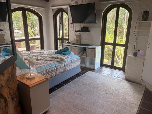 a living room with a couch and a tv and windows at Tropical Spanish Style Cabana - New Listing! in Sydney