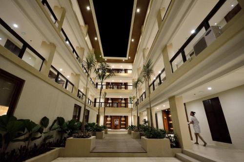 a man walking down a hallway in a building with plants at Henann Resort Alona Beach in Panglao