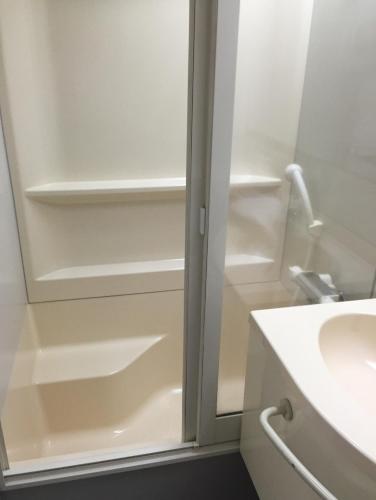 a bathroom with a shower backdoor with a sink at Shinseto Station Hotel in Seto