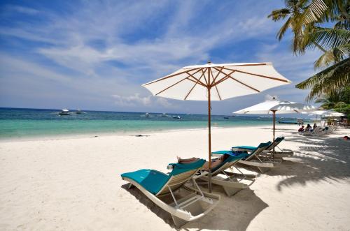 a group of chairs and an umbrella on a beach at Henann Resort Alona Beach in Panglao