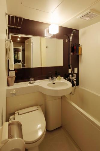 a bathroom with a toilet and a sink and a tub at Candeo Hotels Chino in Chino