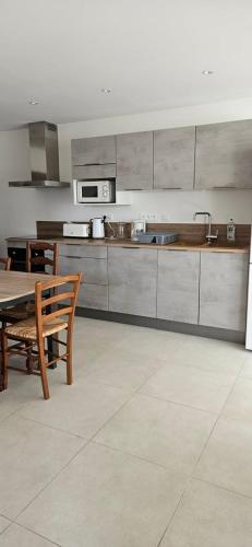 een keuken met een houten tafel en een tafel met stoelen bij Maison au bord du Blavet in Le Pener