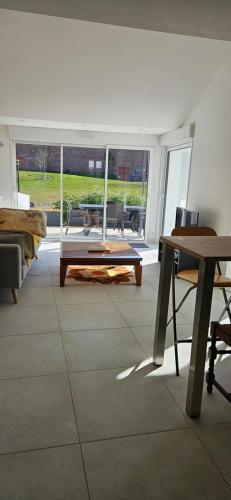 een woonkamer met een tafel en uitzicht op een patio bij Maison au bord du Blavet in Le Pener