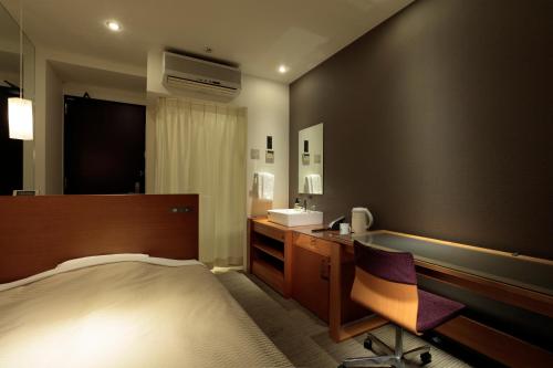 a bedroom with a bed and a sink and a desk at Candeo Hotels Chino in Chino
