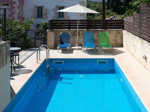 una piscina con due sedie e un ombrellone di Luxurious Villa with Private Pool ad Arménoi