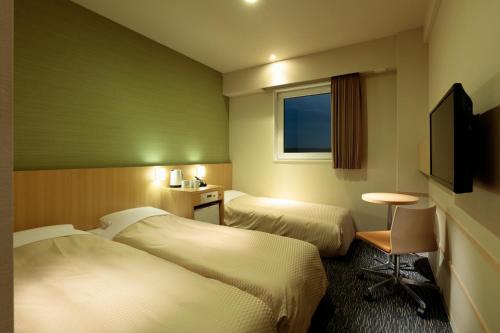 a hotel room with two beds and a television at Candeo Hotels Shizuoka Shimada in Shimada