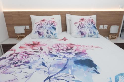 ein Bett mit rosa und lila Blumen darauf in der Unterkunft Le Van G-Home in Auvers-sur-Oise