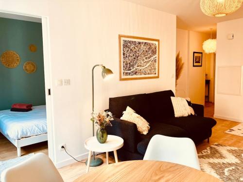 een woonkamer met een zwarte bank en een bed bij Le Cours des Arts in Nantes