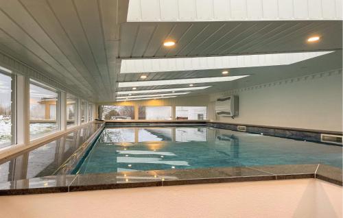 a swimming pool in a building with a large window at Pet Friendly Home In Haarby With Sauna in Brydegård